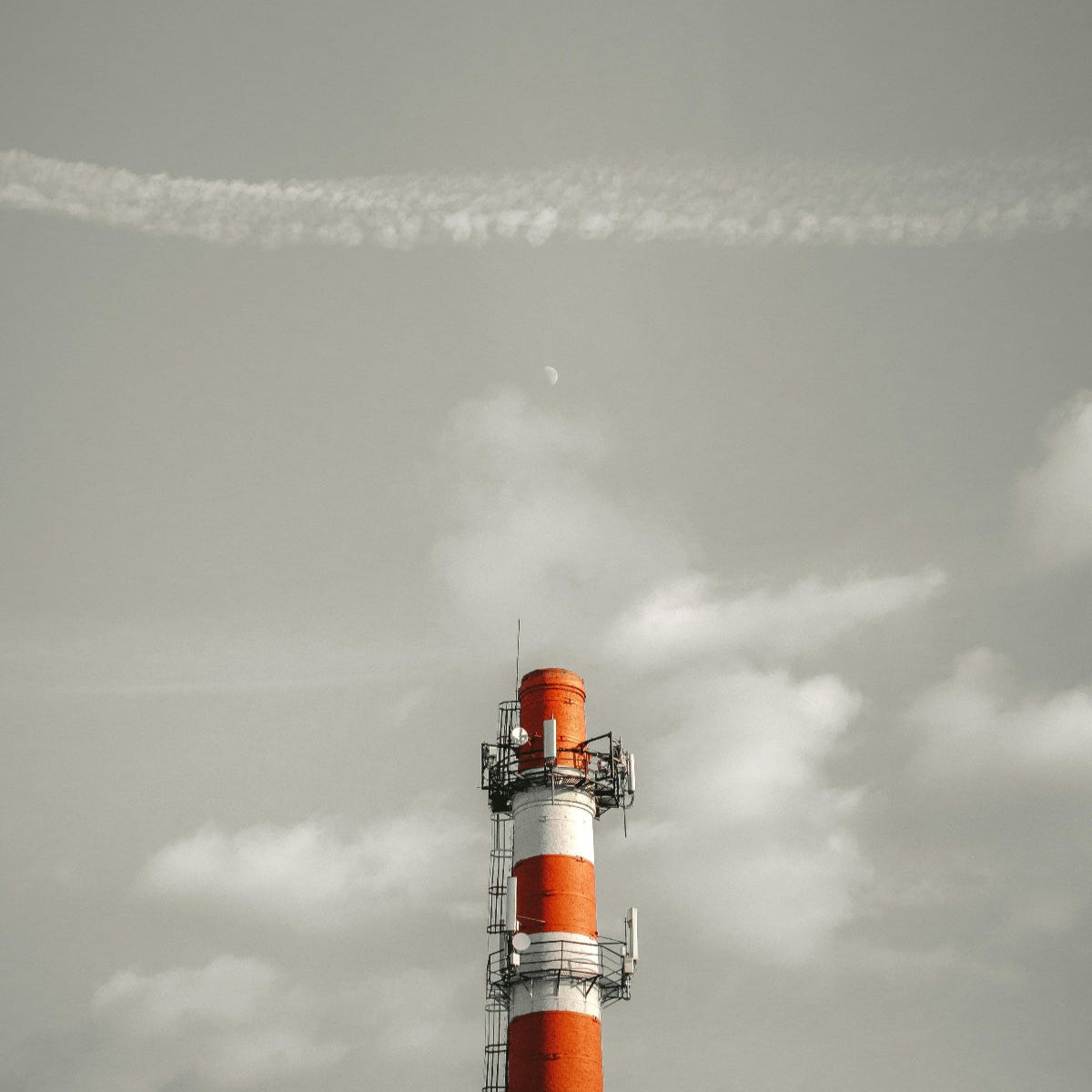 Tall cylindrical industrial structure with red and white stripes against a cloudy sky
